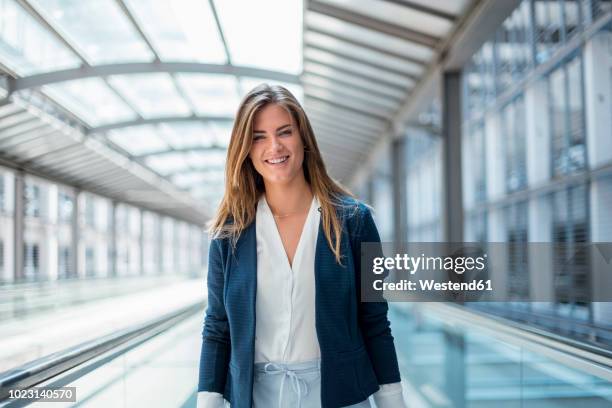 portrait of smiling young businesswoman on moving walkway - travolator stock pictures, royalty-free photos & images