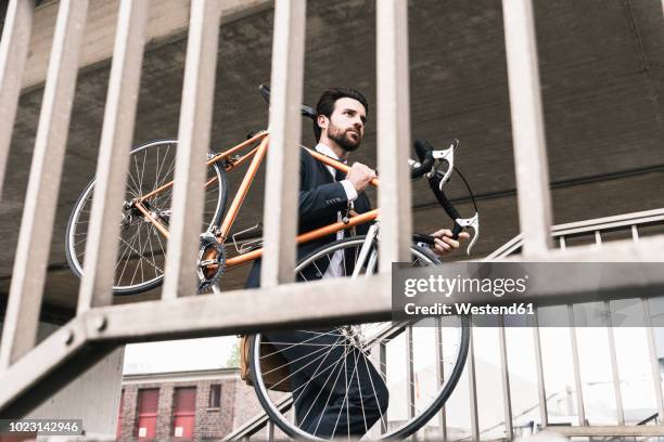 businessman carrying bicycle at the station - schleppe kleidung stock-fotos und bilder