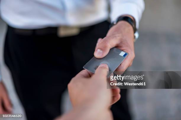 close-up of businessman handing over credit card - debit cards credit cards accepted stock pictures, royalty-free photos & images