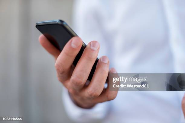 close-up of businessman holding cell phone - hand smartphone stock-fotos und bilder