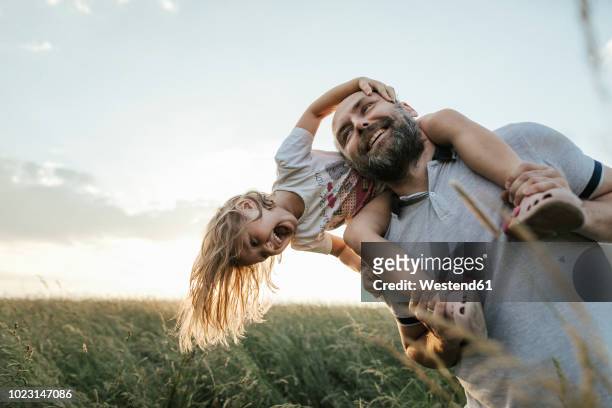mature man playing with his little daughter in nature - rural scene stock-fotos und bilder