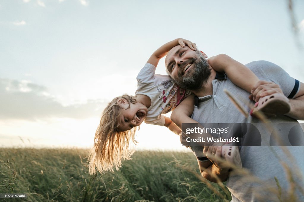 Mature man playing with his little daughter in nature