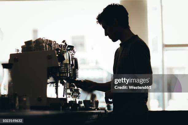 silhouette of barista preparing coffee in a coffee bar - camareros fotografías e imágenes de stock