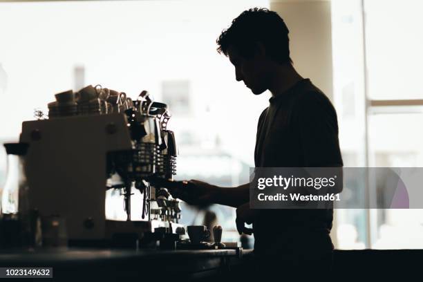 silhouette of barista preparing coffee in a coffee bar - camarero fotografías e imágenes de stock