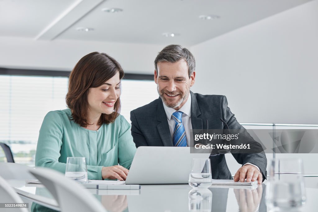 Businessman and businesswoman having a meeting in office with laptop