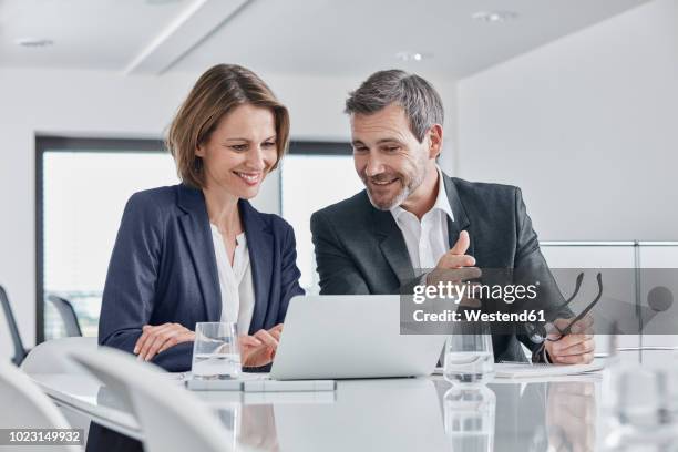 businessman and businesswoman having a meeting in office with laptop - business meeting table stock-fotos und bilder