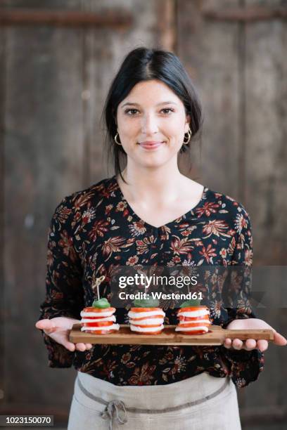 portrait of smiling woman serving caprese salad - mozzarella stock pictures, royalty-free photos & images