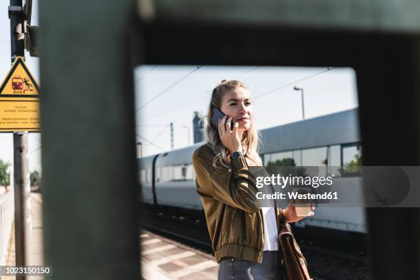 young woman at train station talking at the phone - railroad station platform stock pictures, royalty-free photos & images