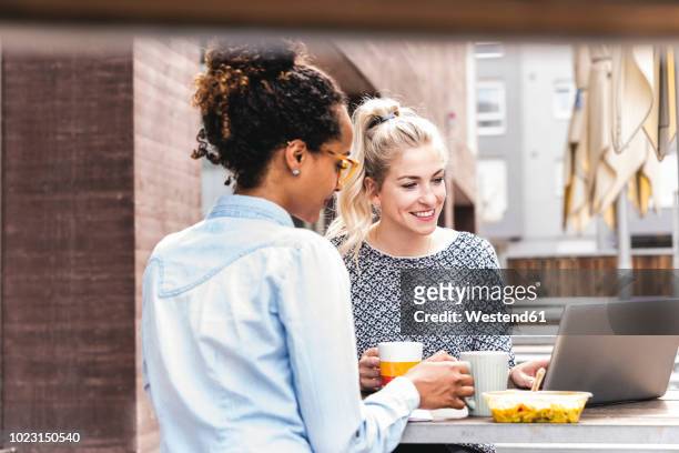 young colleagues sitting outdoors, working together, having lunch - coffee meeting with friends stock pictures, royalty-free photos & images