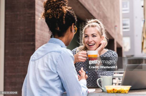 young colleagues sitting outdoors, working together, having lunch - 2 frauen gespräch ohne männer cafe stock-fotos und bilder