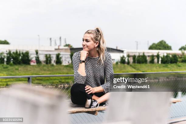 young businesswoman sitting outdoors, taking a break - junge frau allein stock-fotos und bilder