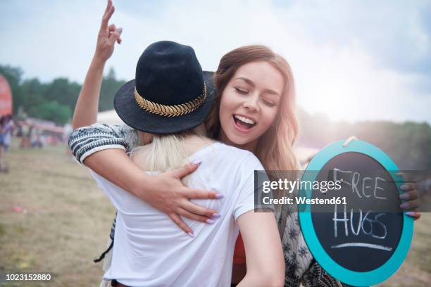 young women embracing during at the music festival - free sign stock pictures, royalty-free photos & images