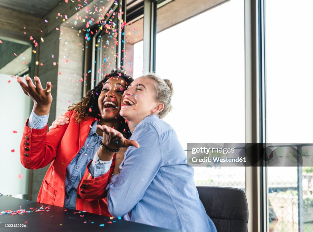 Young busniesswomen celebrating success, throwing confetti