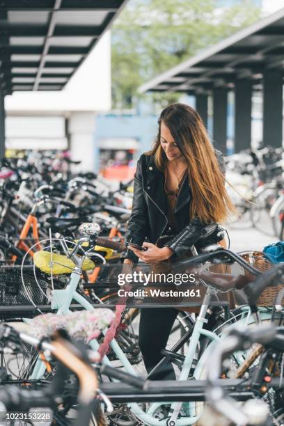 young woman with bicycle using cell phone in the city - fahrradschloss stock-fotos und bilder