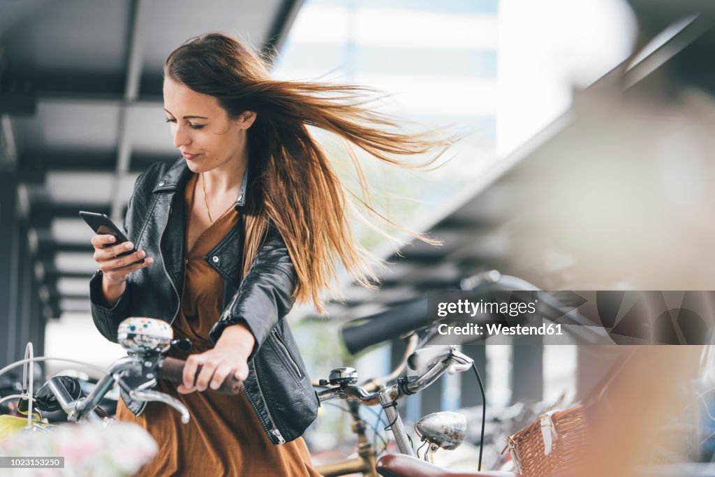 Young woman with bicycle using cell phone in the city