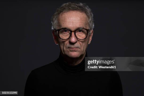 portrait of serious senior man wearing glasses in front of dark background - culotte sur la tête photos et images de collection