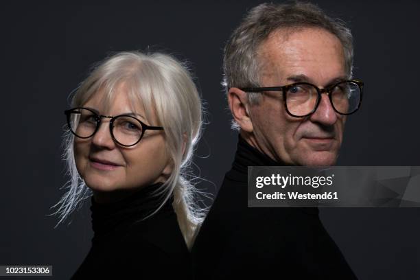 portrait of senior couple wearing glasses in front of dark background - portrait professional dark background stock pictures, royalty-free photos & images