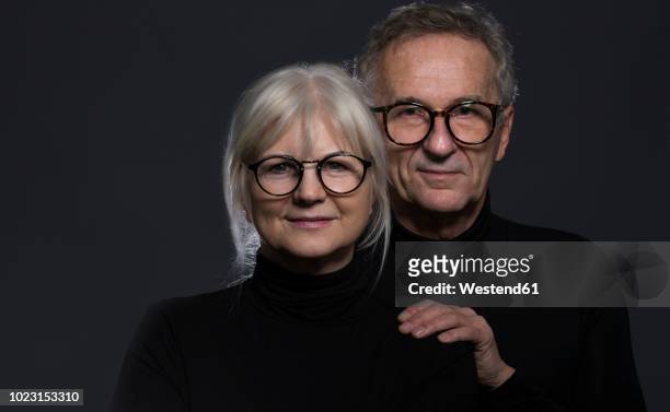 portrait of senior couple wearing glasses in front of dark background - couple dark background stock-fotos und bilder