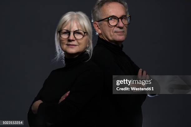 portrait of senior couple wearing glasses in front of dark background - woman black background stock pictures, royalty-free photos & images