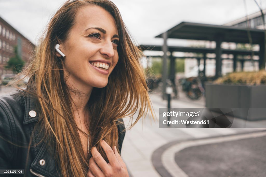 Smiling young woman wearing in-ear phones