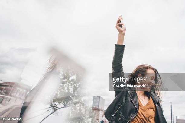 happy young woman with in-ear phones and cell phone - solo una donna giovane foto e immagini stock
