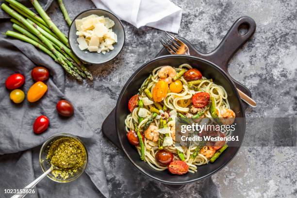 spaghetti with shrimps, green asparagus, tomato, pesto and parmesan - garnaal vis en zeevruchten stockfoto's en -beelden