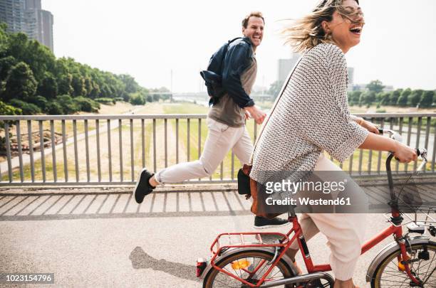 happy couple crossing a bridge with bicycle and by foot - activity stock pictures, royalty-free photos & images