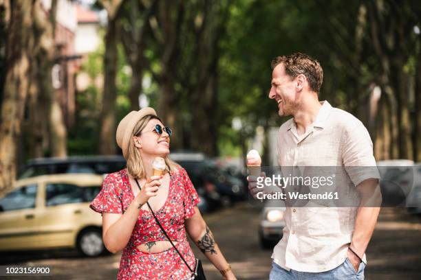 happy couple with ice cream cones walking in the city - essen stadt stock-fotos und bilder