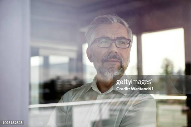 portrait of businessman looking out of window - fenster stock-fotos und bilder