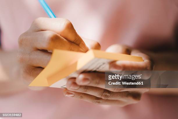 woman writing with pen on adhesive notes - postit stockfoto's en -beelden