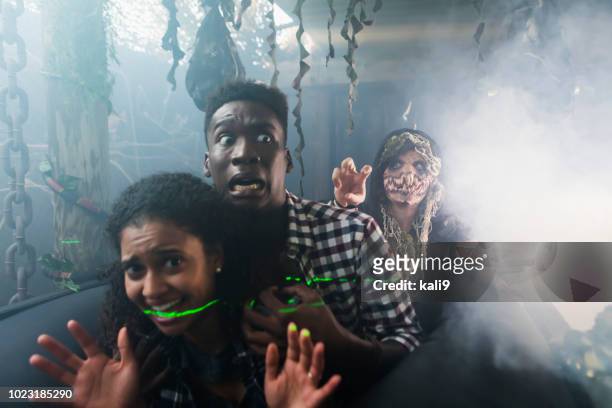 young couple with zombie in halloween haunted house - spooky stock pictures, royalty-free photos & images