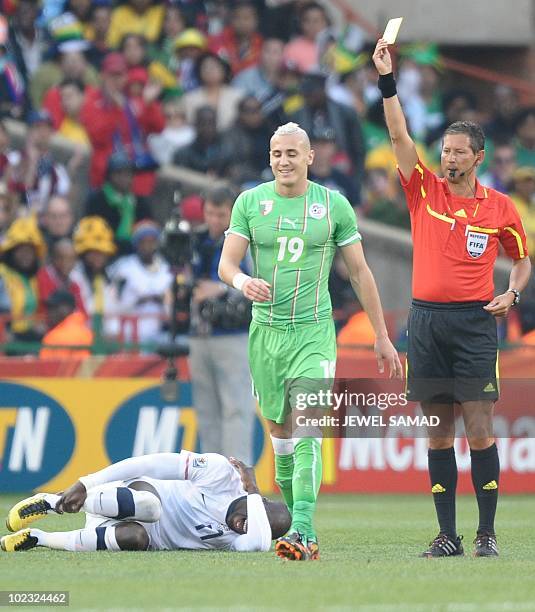 Belgian referee Frank De Bleeckere gives a yellow card to Algeria's midfielder Hassan Yebda as US striker Jozy Altidore lays on the pitch during...