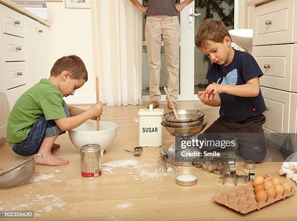 mother catching twins baking and messing floor  - woman smile kitchen foto e immagini stock
