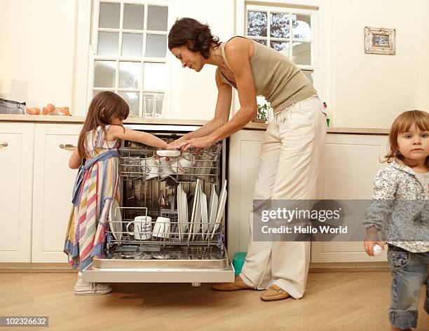 little girl helping her mother load dishwasher - loading dishwasher stock pictures, royalty-free photos & images