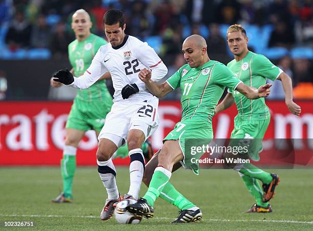 Benny Feilhaber of the United States is tackled by Rafik Djebbour of Algeria during the 2010 FIFA World Cup South Africa Group C match between USA...