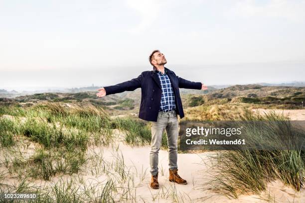 man standing in dunes with outstretched arms - evasión fotografías e imágenes de stock