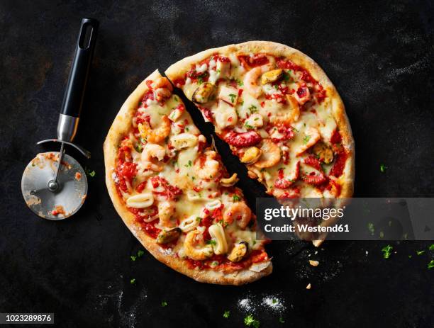 sliced pizza with frutti di mare on dark ground - ピザカッター ストックフォトと画像