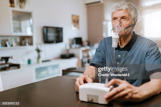 senior man using inhaler at home - nebulizer stock pictures, royalty-free photos & images