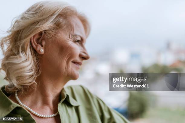 smiling senior woman with hearing aid outdoors - hearing aid - fotografias e filmes do acervo