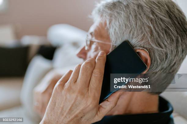 senior man with hearing aid on cell phone - ears photos et images de collection