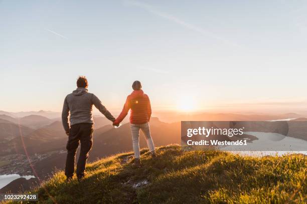 austria, salzkammergut, couple standing on mountain summit, enjoying the view - activities in the sun stockfoto's en -beelden