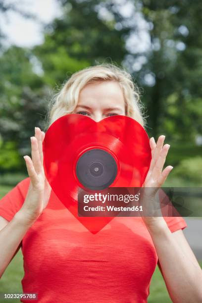 woman holding a heart-shaped vinyl record outdoors - album cover stock-fotos und bilder