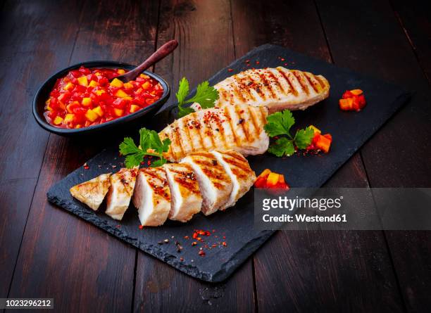 chicken breast fillet with bell pepper chutney on slate - hühnchenbrust stock-fotos und bilder