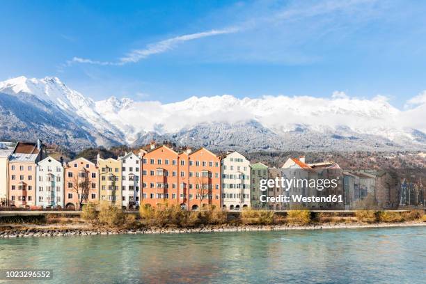 austria, innsbruck, row of houses in front of nordkette mountains with inn river in the foreground - stato federato del tirolo foto e immagini stock