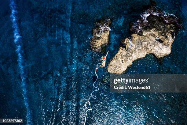 greece, crete, bungee jumping, woman jumping bungee over sea - bunjee jumping stock-fotos und bilder