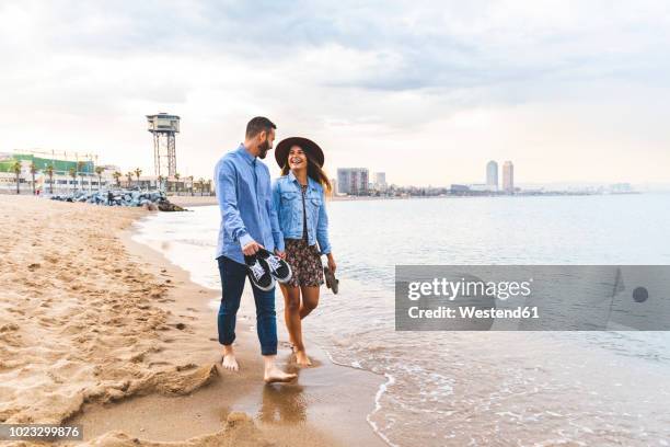 spain, barcelona, couple walking barefoot on the beach - young couple holding hands stock pictures, royalty-free photos & images