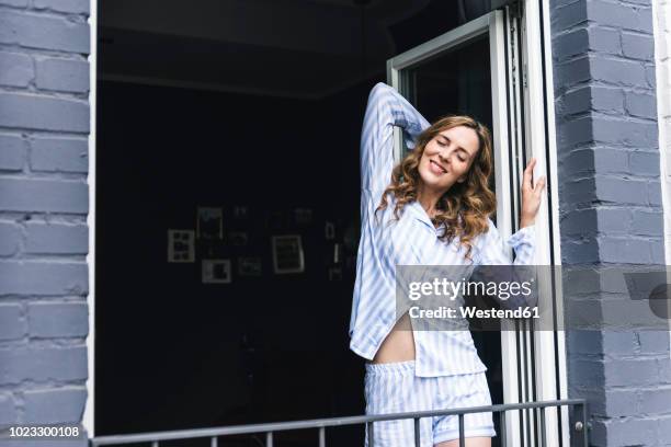 smiling woman in pyjama at home stretching at the balcony - pijama imagens e fotografias de stock