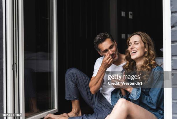 happy couple in nightwear at home sitting at french window - coffee at home imagens e fotografias de stock