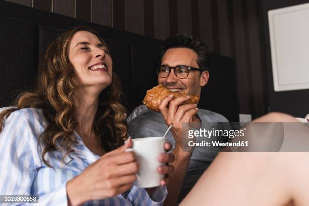 happy couple having breakfast in bed at home - sharing coffee stockfoto's en -beelden