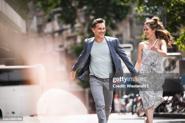 happy carefree couple running in the city - happy people running stockfoto's en -beelden